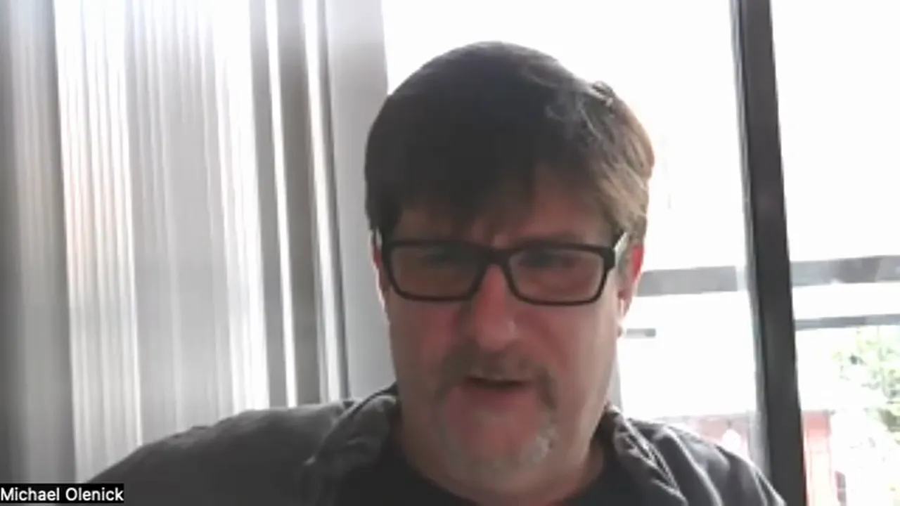 Well-centered, sharp screenshot of a presenter in front of a window during a video presentation; good lighting and focus.