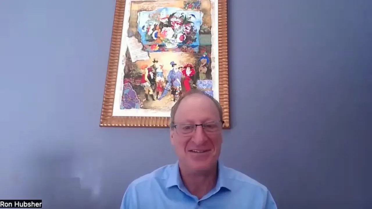 Presenter on a virtual call, centered and smiling with framed artwork behind