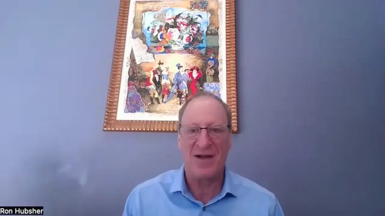 Presenter on a virtual call mid-speech with framed artwork behind them