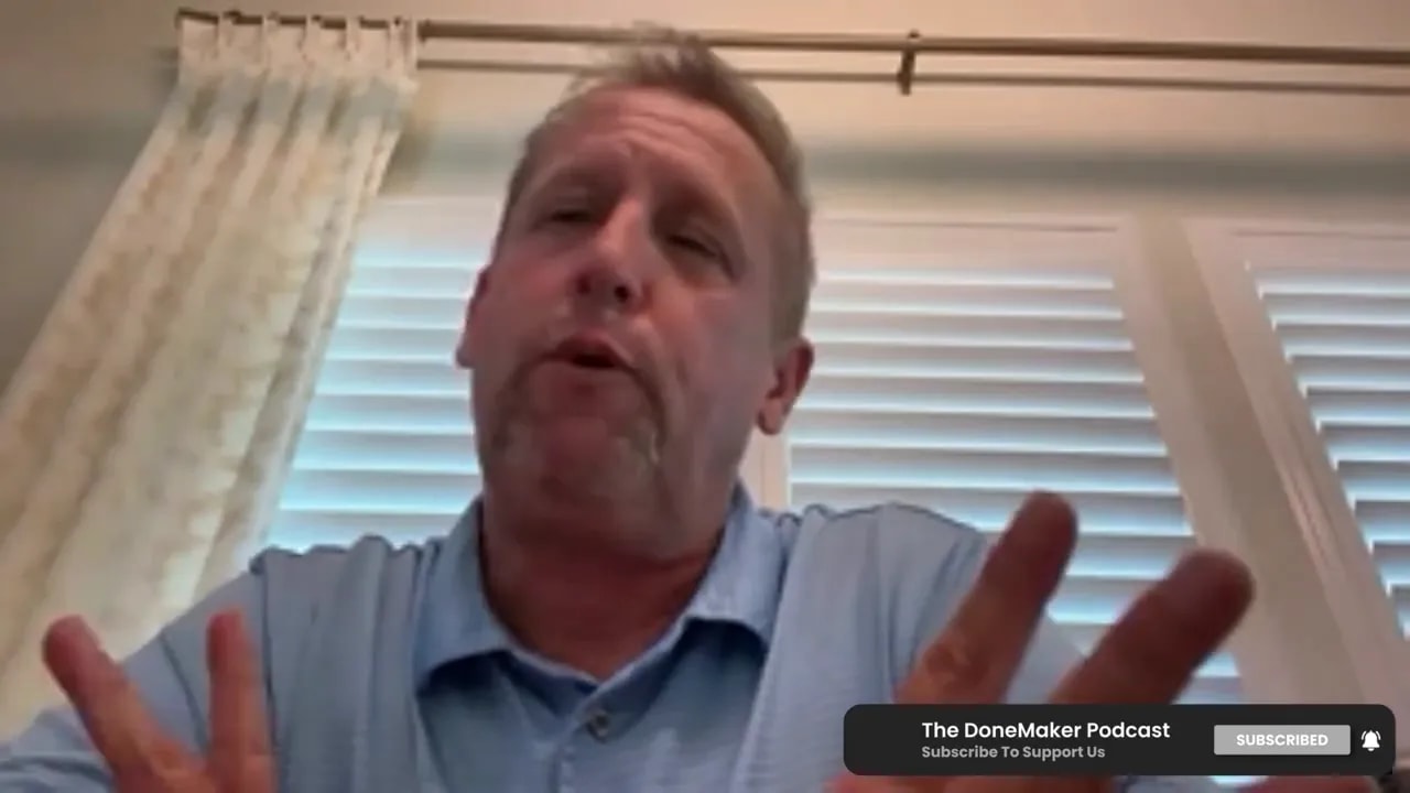 Podcast speaker gesturing with both hands while explaining, window blinds and curtain behind him.