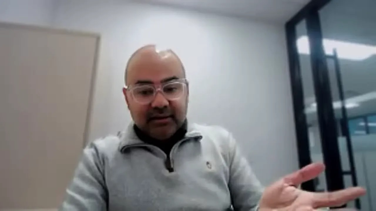 Person in an office on video call gesturing with an open hand while explaining when to apply for grants and tax credits