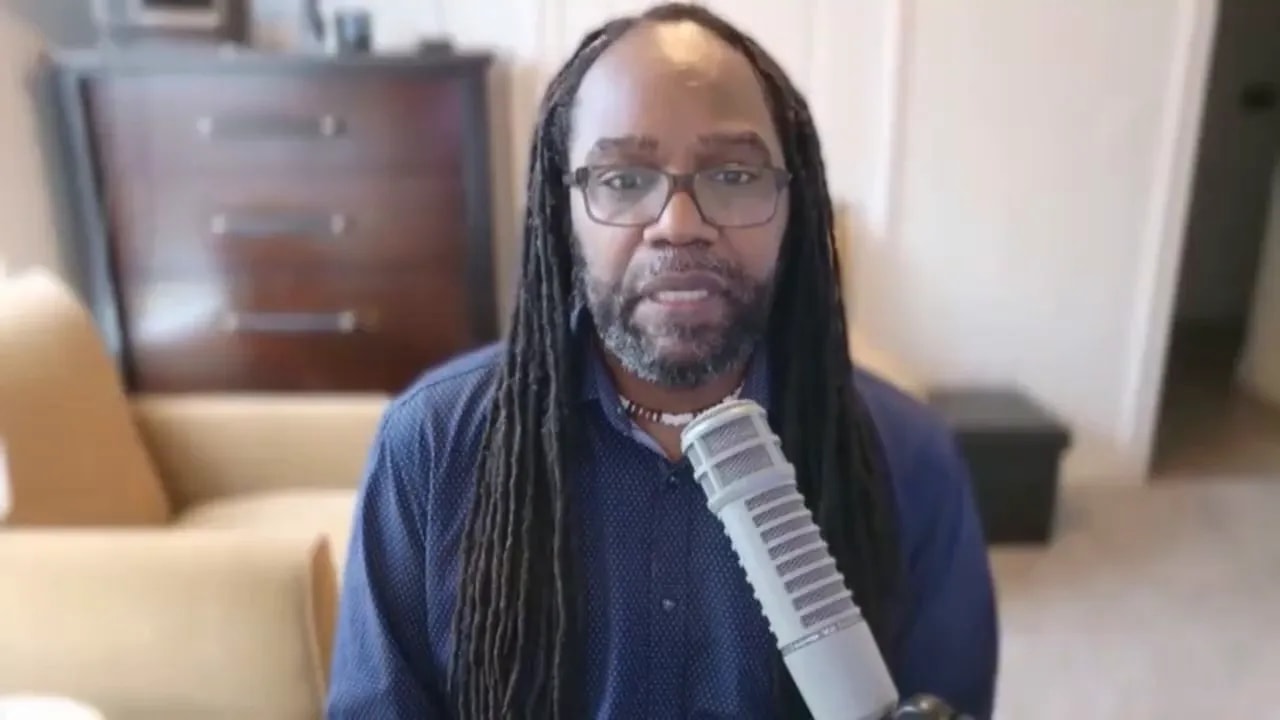 Speaker centered on camera speaking into a microphone, clear and focused framing