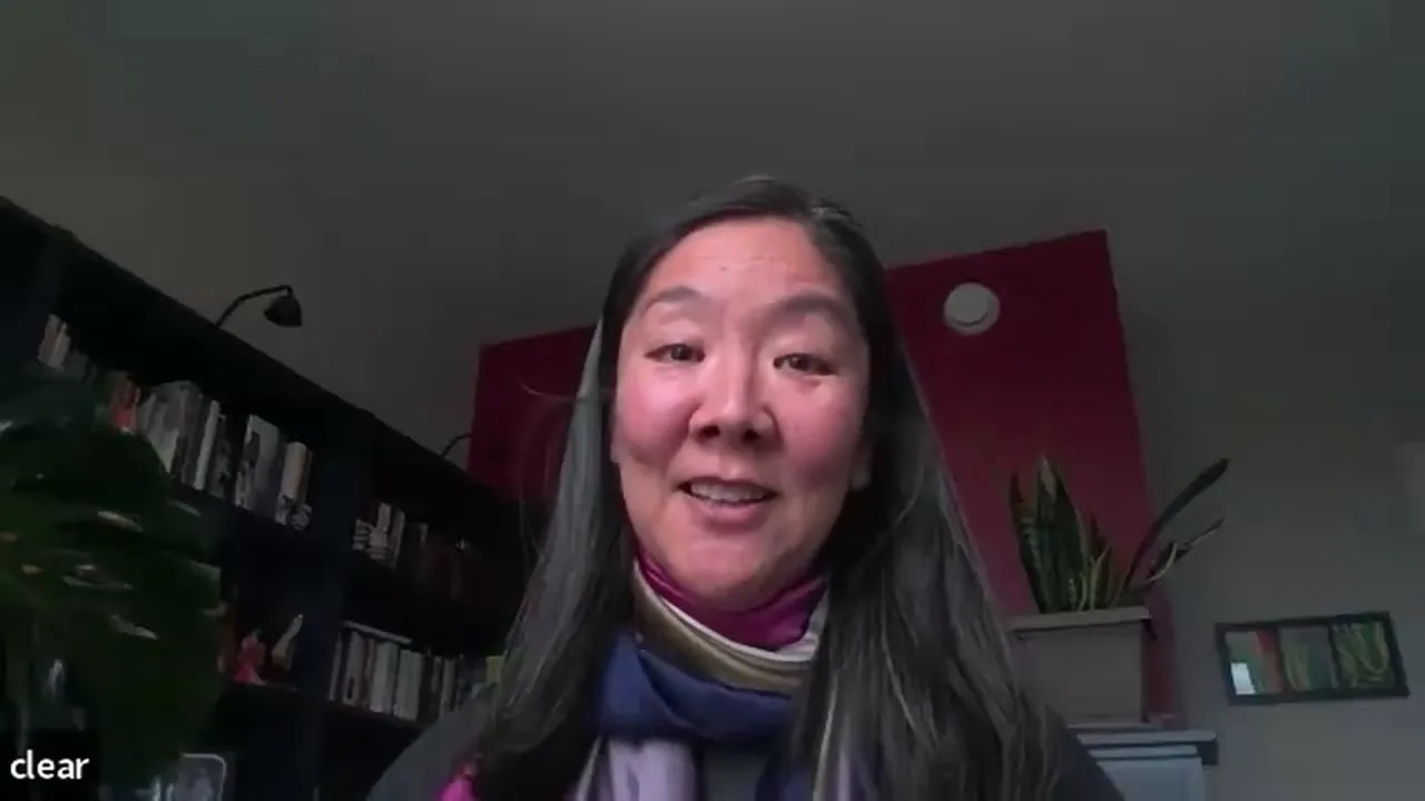 Smiling person on a video call with bookshelf and plant behind them, conveying approachability