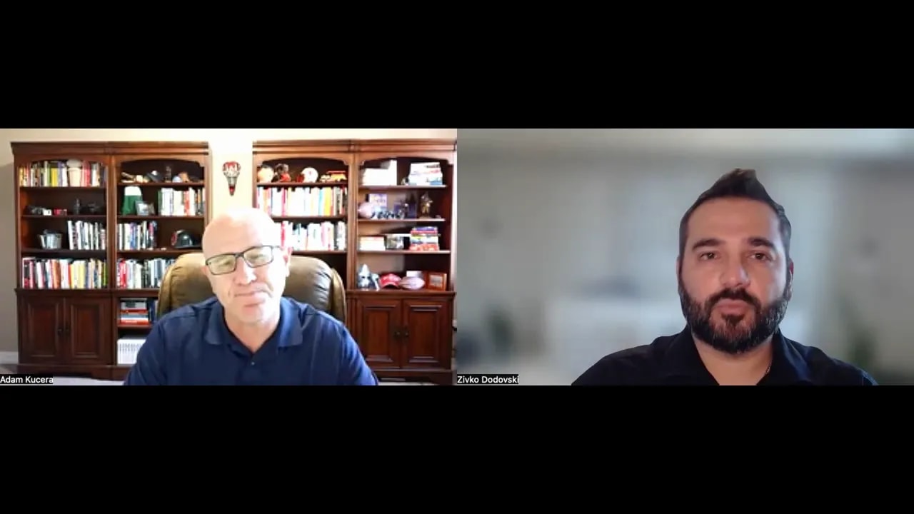 Two people on a video call, both visible and well-framed, left participant seated in front of a bookshelf and right participant against a blurred background; professional discussion screenshot.